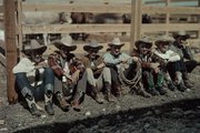 Cowboyok és rodeórésztvevők ülnek egy kerítés előtt a San Antonio-i Rodeó idején