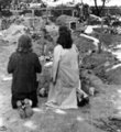 Két nő térdepel a varsói Mazowiecka utca közelében lévő, sebtében eltemetett elhunytak sírhalmai előtt (1944)