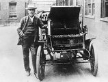 Thomas Edison első elektromos autója mellett 1895-ben, kezében az egyik cserélhető elemet tartja
