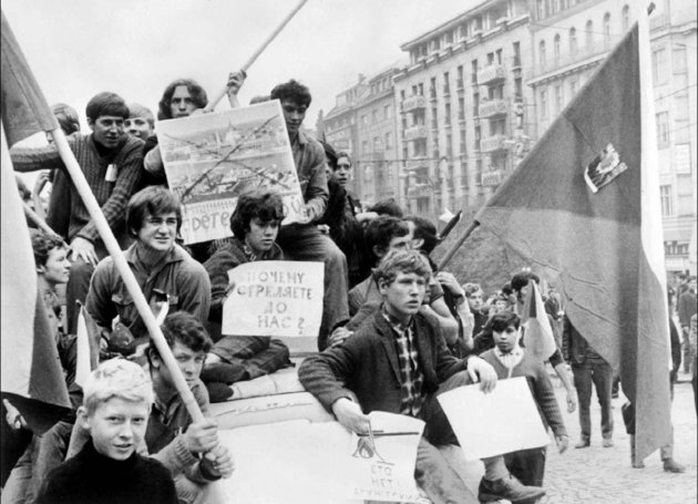 Cseh fiatalok nemzeti lobogóval és „Miért lőtök ránk?” feliratú plakátokkal