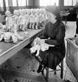 Egy munkásnő ruhákat ad a babákra egy párizsi gyárban 1945. december 3-án 