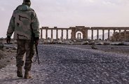 A szíriai hadsereg katonája sétál a palmürai romoknál