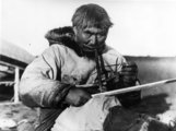 Egy inuit asztalos hagyományos fúróval, amelyet a szájával tart, az egyik kezével pedig a zsinórt húzza, amivel eléri, hogy forogjon a fúrófej (1910 körül)