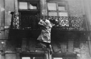 Egy nő egy égő ház erkélyébe kapaszkodva próbál biztonságosan leereszkedni, 1943.
