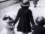 Az Egyesült Királyság egyik városában egy nő viszi kézen fogva gyermekeit. Mindannyiuk fejét sisak védi.