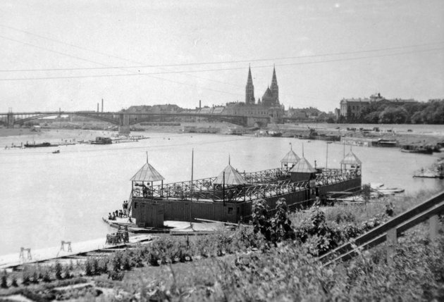 Előtérben egy Tisza-parti fürdő, háttérben a régi közúti híd és a Fogadalmi templom (1929) (Fortepan / Fortepan)