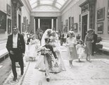 Diana legfiatalabb koszorúslányával a karján sétál keresztül a Buckingham-palotán. Mellette újdonsült anyósa, II. Erzsébet királynő