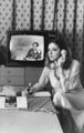 Mindenki telefonál. Rák Kati színésznő, háttérben a televízió képernyőjén Vitray Tamás, 1979. (Fortepan/Rádió és Televízió Újság)