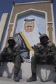 Amerikai katonák pihennek meg egy Szaddám Huszeint ábrázoló nagyméretű falfestmény mellett valahol Irakban