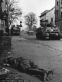 Az amerikai 9. páncéloshadosztály csapatai haladnak el egy utcán heverő holttest mellett 1945 áprilisában   <br /><i>John Florea/Steven Kasher Gallery</i>