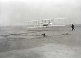 A motoros Wright Flyer levegőbe emelkedése, 1903. december 17. A pilóta Orville, mellette a földön Wilbur látható.