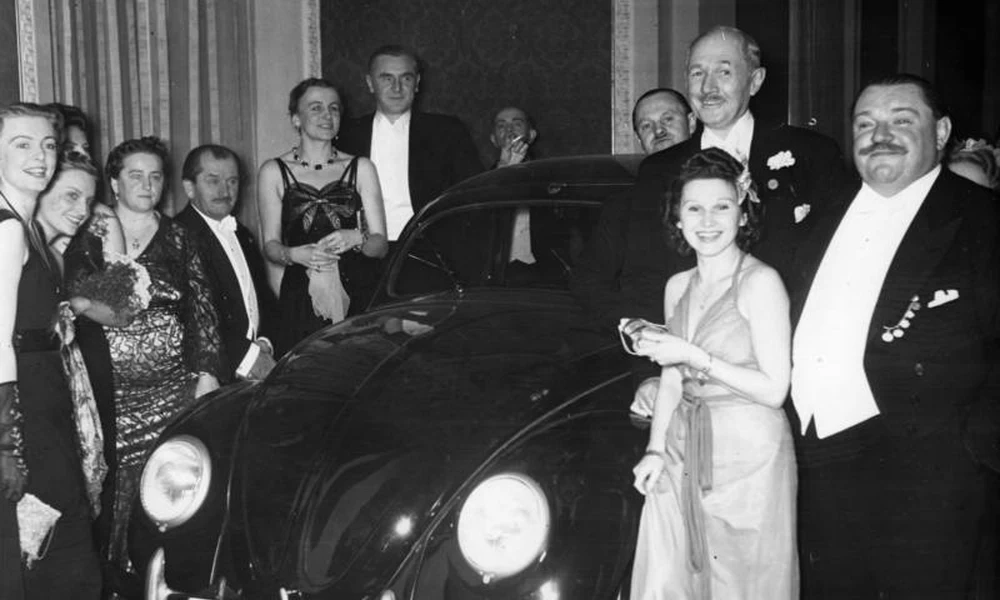 Ferdinand Porsche (balról a negyedik) a Volkswagen tombolanyeremény átadásán 1939 januárjában a szerencsés nyertessel.