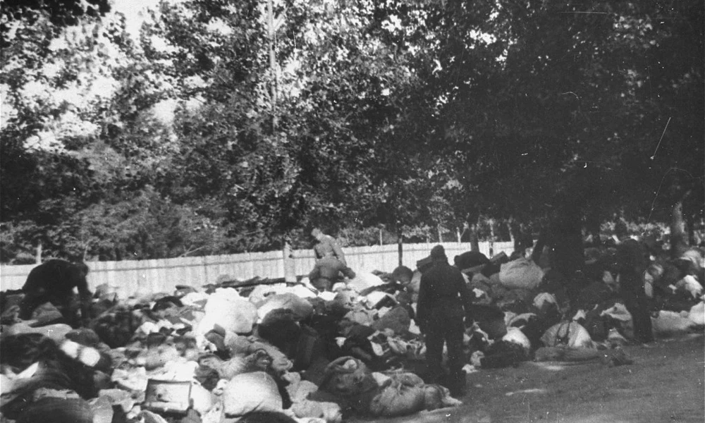 Az Einsatzgruppe (mozgó kivégzőosztag) C azonosítatlan egységeihez tartozó katonák a Kijev közeli Babij Jar szakadékban lemészárolt zsidók tárgyai között kutatnak. Szovjetunió, 1941. szeptember 29–október 1. Fotó: US Holocaust Memorial