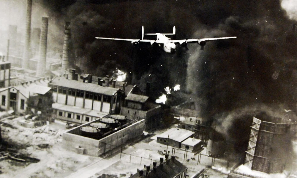 Amerikai B–24 Liberator bombázó repül a lángoló ploiești-i olajfinomító fölött 1943. augusztus 1-jén