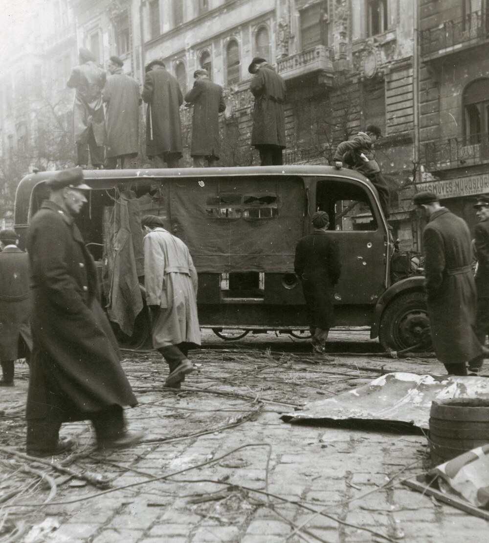 Nézelődők láthatók egy Csepel rendőrségi rohamkocsi roncsa mellett a Tompa utcánál